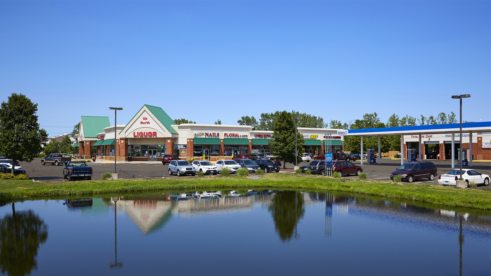 Pinebrook Centre Brooklyn Park MN retail strip mall full view shot from across pond