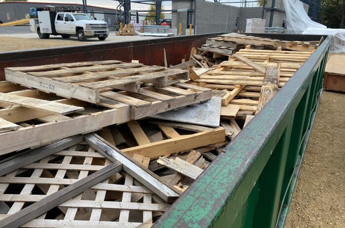 dumpster filled with wood pallets for recycling