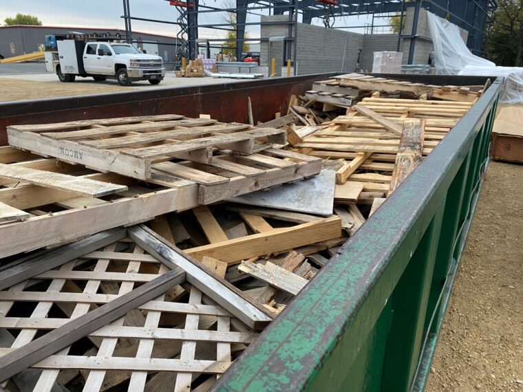 dumpster filled with wood pallets for recycling