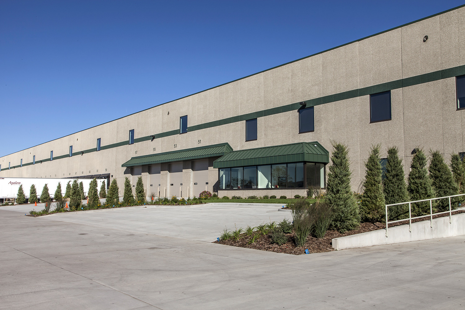 "Uline was begun in 1980 in the basement of the owners’ home. The first product offered was the H-101 carton sizer, which is still offered today. Uline has grown steadily since 1980 and continues to be a family owned and operated business. Today, with over 2,500 employees nationwide, Uline has distribution centers near Chicago, IL; Minneapolis, MN; Allentown, PA; Los Angeles, CA; Atlanta, GA; Dallas, TX; Seattle, WA; Tijuana, Mexico; Monterrey, Mexico and near Toronto, Ontario. The new Uline Distribution Warehouse, constructed by Kraus-Anderson, is located in Hudson, WI at Highway 35 and Hanley Road. The project was constructed on a 62.5 acre site. The 646,000 s.f. facility consists of 610,000 s.f. of warehousing with a 32’ clear height at the first column line and 36,000 s.f. of office space. The site development, including underground utilities, storm water ponds, erosion control, grading and landscaping was included in the scope of work. Exterior pavements include a concrete truck court area and bituminous parking areas. This building is a cross-dock warehouse with approximately 182 dock positions with parking for 200 additional trailers. Primary construction is IBC Type 2B, non-combustible, fully sprinklered, utilizing pre-cast concrete wall panels with steel structure and ballasted EPDM roofing over metal deck. Uline stores contents that are classified as Commodities I-IV per the NFPA 1 Fire Code, necessitating ESFR sprinkler coverage in the warehouse. The office space is two stories in height, with a pre-cast concrete plank 2nd floor supported on a structural steel frame, plus structural steel roof framing. One hydraulic elevator provides accessibility to 2nd floor with parking for 250 employees."