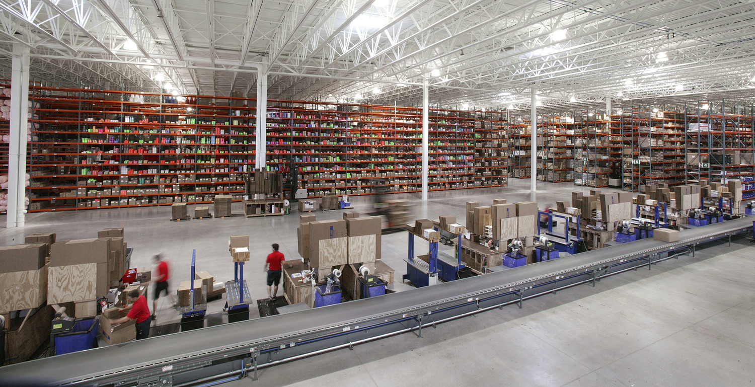 "Uline was begun in 1980 in the basement of the owners’ home. The first product offered was the H-101 carton sizer, which is still offered today. Uline has grown steadily since 1980 and continues to be a family owned and operated business. Today, with over 2,500 employees nationwide, Uline has distribution centers near Chicago, IL; Minneapolis, MN; Allentown, PA; Los Angeles, CA; Atlanta, GA; Dallas, TX; Seattle, WA; Tijuana, Mexico; Monterrey, Mexico and near Toronto, Ontario. The new Uline Distribution Warehouse, constructed by Kraus-Anderson, is located in Hudson, WI at Highway 35 and Hanley Road. The project was constructed on a 62.5 acre site. The 646,000 s.f. facility consists of 610,000 s.f. of warehousing with a 32’ clear height at the first column line and 36,000 s.f. of office space. The site development, including underground utilities, storm water ponds, erosion control, grading and landscaping was included in the scope of work. Exterior pavements include a concrete truck court area and bituminous parking areas. This building is a cross-dock warehouse with approximately 182 dock positions with parking for 200 additional trailers. Primary construction is IBC Type 2B, non-combustible, fully sprinklered, utilizing pre-cast concrete wall panels with steel structure and ballasted EPDM roofing over metal deck. Uline stores contents that are classified as Commodities I-IV per the NFPA 1 Fire Code, necessitating ESFR sprinkler coverage in the warehouse. The office space is two stories in height, with a pre-cast concrete plank 2nd floor supported on a structural steel frame, plus structural steel roof framing. One hydraulic elevator provides accessibility to 2nd floor with parking for 250 employees."